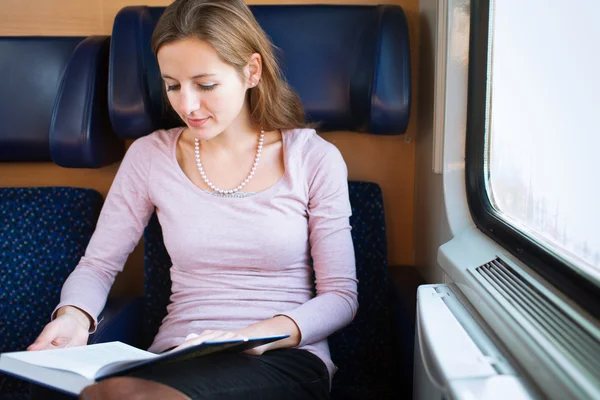 Giovane donna che legge un libro mentre è in treno — Foto Stock