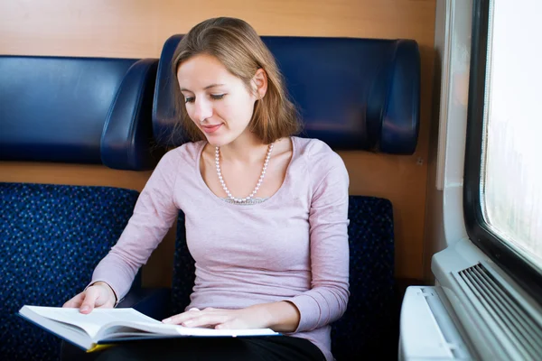 Mujer joven leyendo un libro mientras está en un tren —  Fotos de Stock