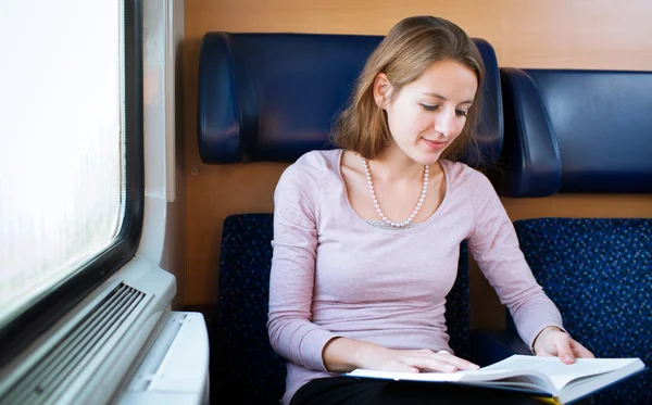 Jovem mulher lendo um livro em um trem — Fotografia de Stock