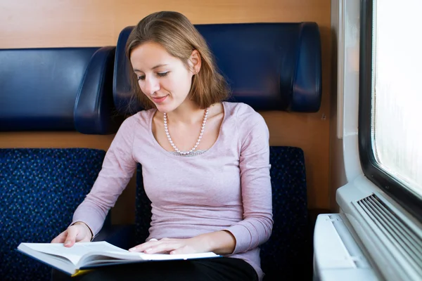 Młoda kobieta, czytanie książki, podczas gdy w pociągu — Zdjęcie stockowe