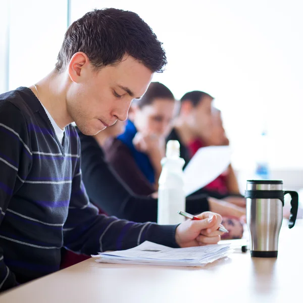 Jovem, bonito estudante universitário masculino sentado em uma sala de aula — Fotografia de Stock