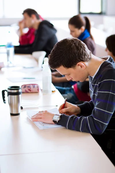 Junge, gut aussehende männliche College-Studentin sitzt in einem Klassenzimmer — Stockfoto