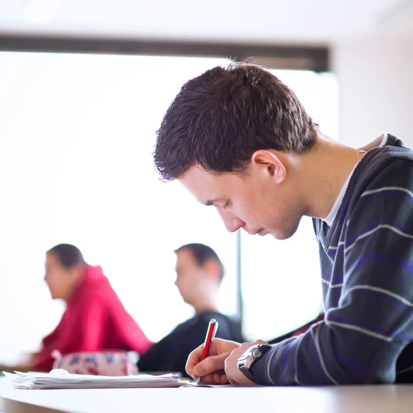 Joven y guapo estudiante universitario sentado en un salón de clases —  Fotos de Stock