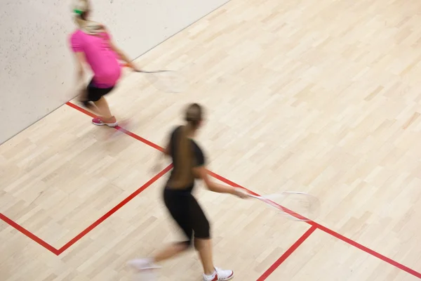Two female squash players in fast action on a squash court — Stock Photo, Image