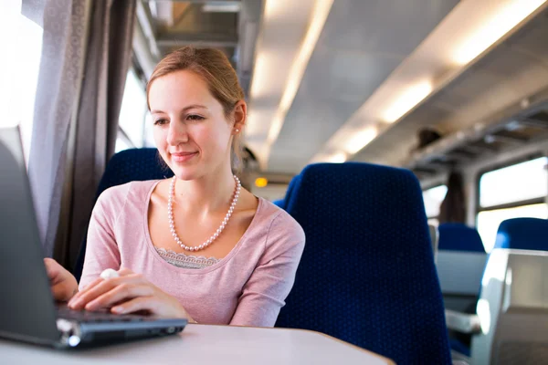 Mujer joven usando su computadora portátil mientras está en el tren — Foto de Stock