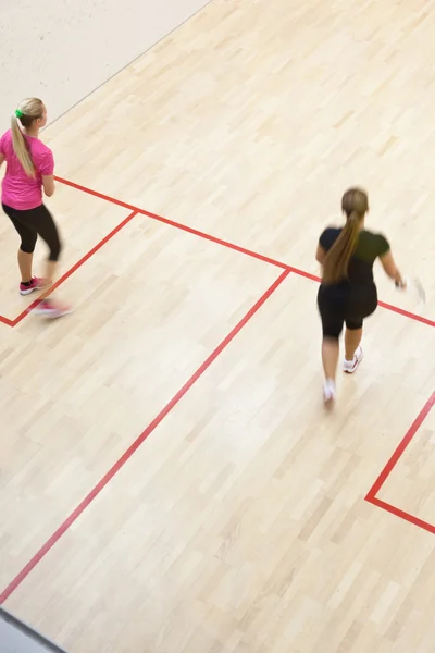 Twee vrouwelijke squash spelers in snelle actie op een squashbaan — Stockfoto