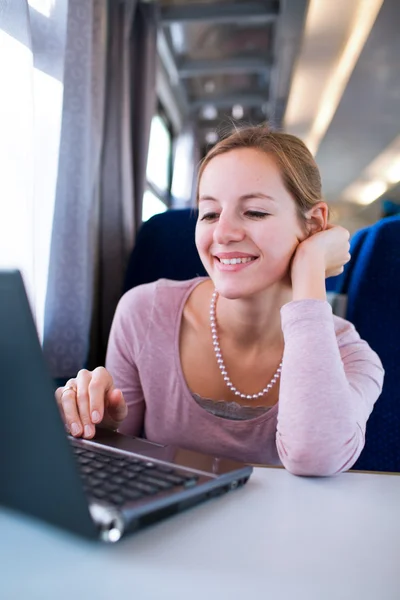 Young woman using her laptop computer while on the train — Stock Photo, Image