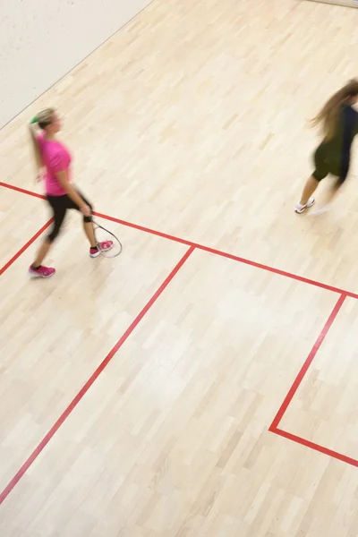 Twee vrouwelijke squash spelers in snelle actie op een squashbaan — Stockfoto