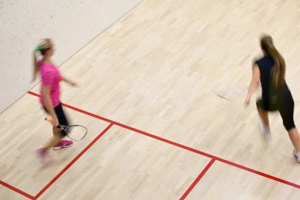 Två kvinnliga squash spelare i snabb action på en squashbana — Stockfoto