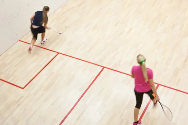 Duas jogadoras de squash em ação rápida em uma quadra de squash — Fotografia de Stock