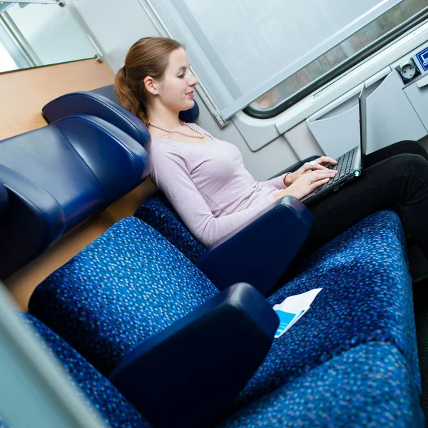 Mujer joven usando su computadora portátil mientras está en el tren — Foto de Stock