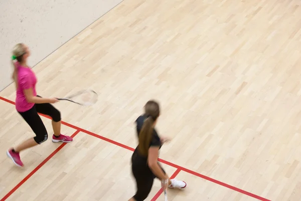 Twee vrouwelijke squash spelers in snelle actie op een squashbaan — Stockfoto