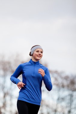 Portrait of a woman running against against blue sky