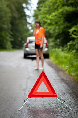 Genç bayan sürücü yol kenarındaki servisi arıyor.