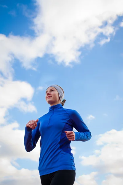 Retrato de uma mulher que corre contra o céu azul — Fotografia de Stock