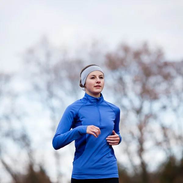 Portrét ženy běh proti proti modré obloze — Stock fotografie