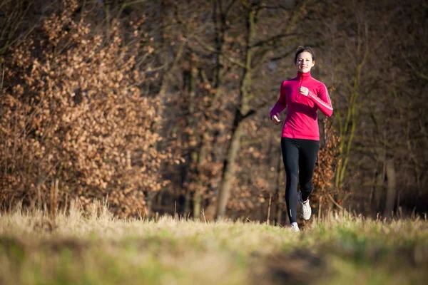 Giovane donna che corre all'aperto in un parco cittadino su una fredda caduta — Foto Stock