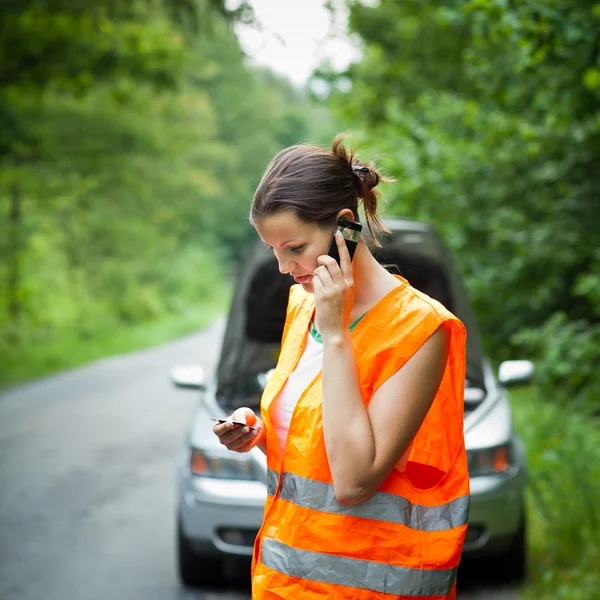 Jonge vrouwelijke bestuurder belt de wegenwacht — Stockfoto