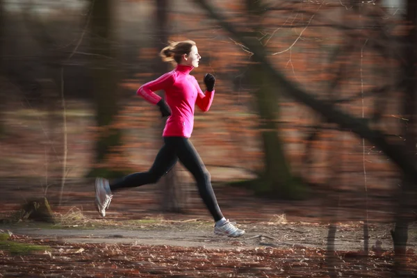 Giovane donna che corre all'aperto in un parco cittadino su una fredda caduta — Foto Stock