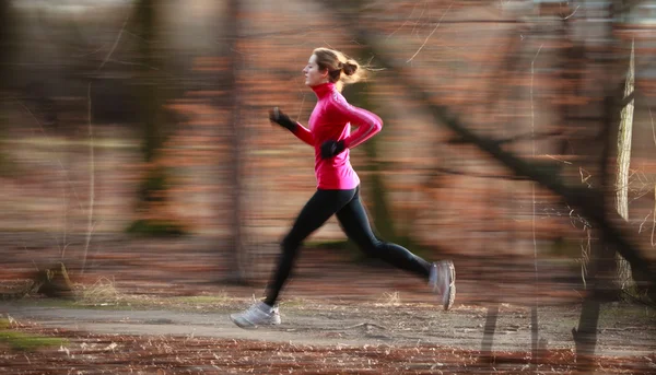 Mujer joven corriendo al aire libre en un parque de la ciudad en una caída fría —  Fotos de Stock