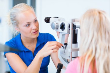 Pretty, young female patient having her eyes examined clipart