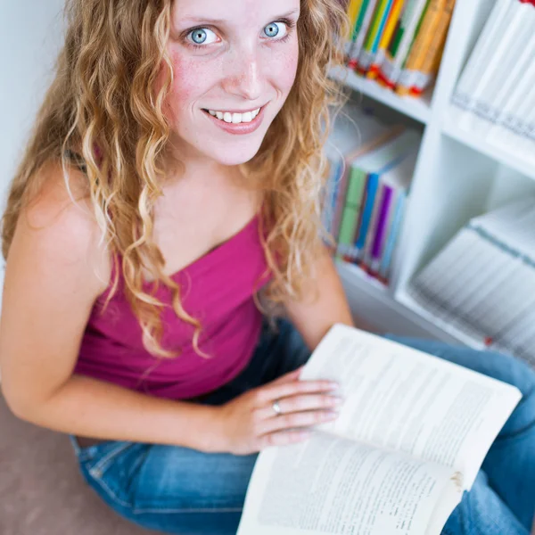 Ganska kvinnliga collegestudent i ett bibliotek — Stockfoto