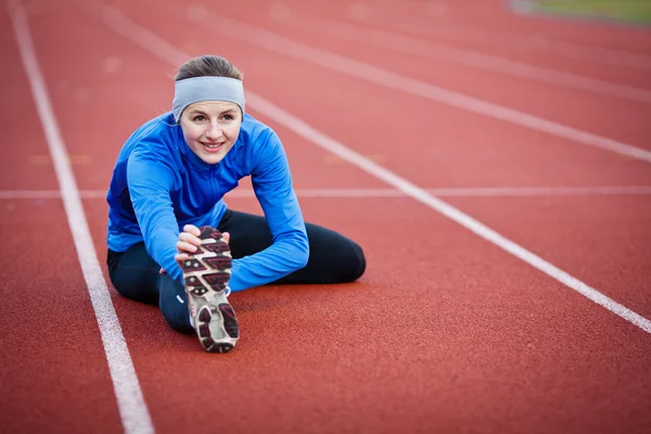 Mladá žena, táhnoucí se před její běh — Stock fotografie