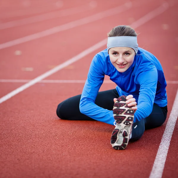 Mladá žena, táhnoucí se před její běh — Stock fotografie