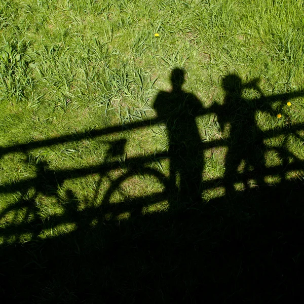 Las siluetas de dos ciclistas de montaña durante un alto en un puente —  Fotos de Stock