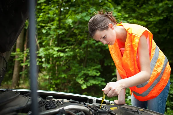 Junge Fahrerin bückt sich über den Motor ihres kaputten Autos — Stockfoto