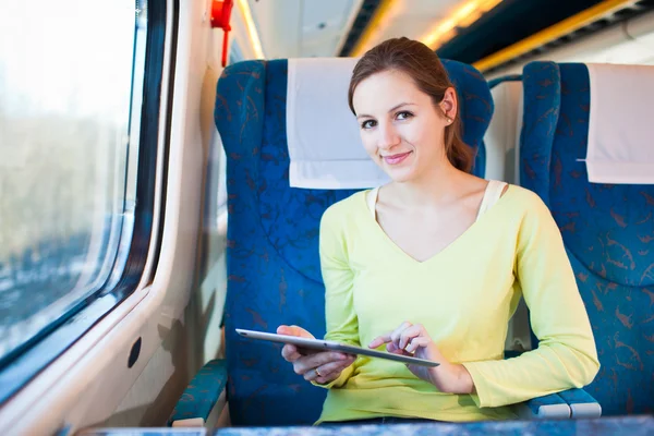 Молодая женщина, путешествуя на поезде, пользуется планшетным компьютером — стоковое фото