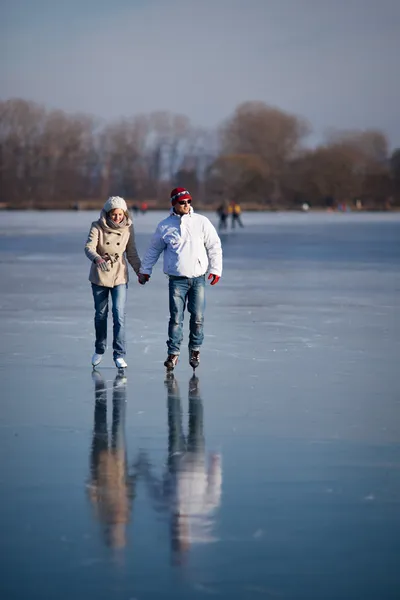 Paar schaatsen buitenshuis op een vijver op een mooie zonnige winterdag — Stockfoto