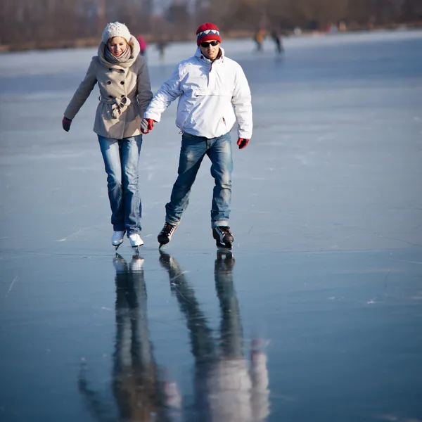 Paar Eislaufen im Freien auf einem Teich an einem schönen sonnigen Wintertag — Stockfoto