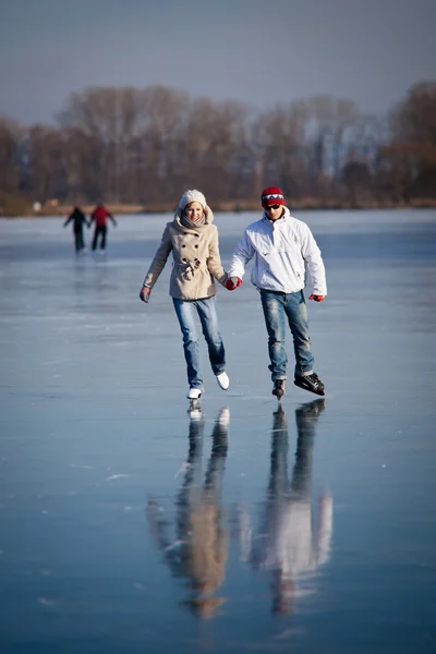 Пара катаний на коньках на открытом воздухе на пруду в прекрасный солнечный зимний день — стоковое фото