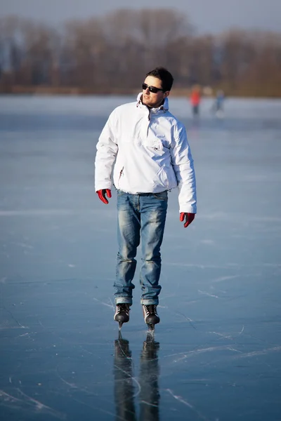 Красивый молодой человек катается на коньках на пруду — стоковое фото