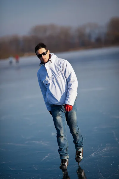 Guapo joven patinaje sobre hielo al aire libre en un estanque — Foto de Stock