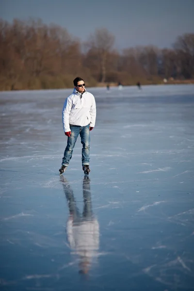 Przystojny, młody człowiek lodu łyżwiarskie na zewnątrz na stawie — Zdjęcie stockowe