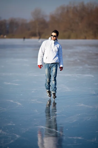 Bello giovane uomo pattinaggio su ghiaccio all'aperto su uno stagno — Foto Stock