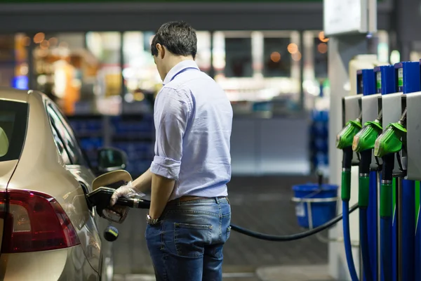 Jovem abastecendo seu carro no posto de gasolina — Fotografia de Stock