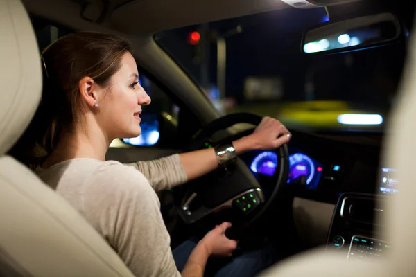Mulher dirigindo seu carro moderno à noite em uma cidade — Fotografia de Stock