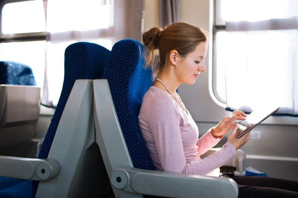 Νεαρή γυναίκα χρησιμοποιώντας το δισκίο σε τρένο — Φωτογραφία Αρχείου