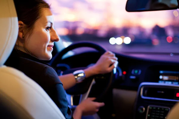 Mujer conduciendo su coche moderno por la noche en una ciudad — Foto de Stock