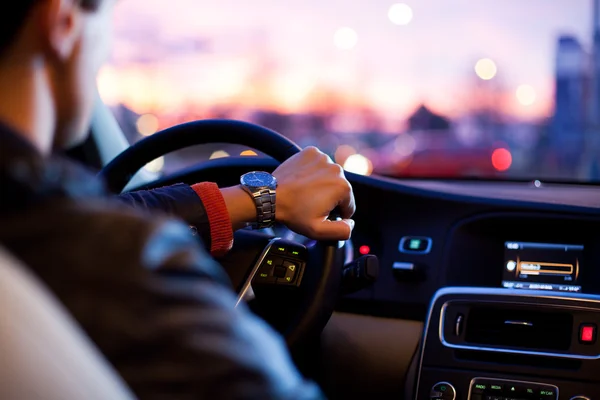 Homme conduisant sa voiture moderne la nuit dans une ville — Photo