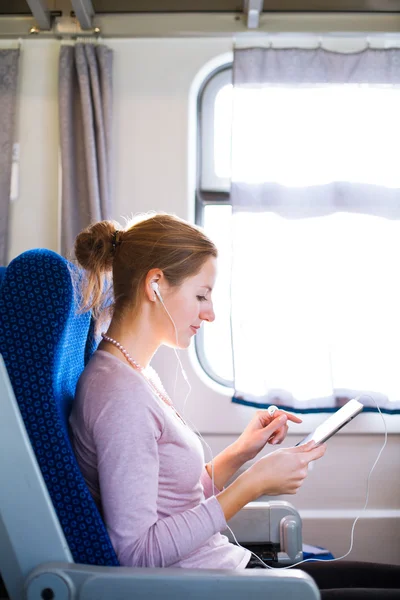 Młoda kobieta za pomocą jej tabletki w pociągu — Zdjęcie stockowe