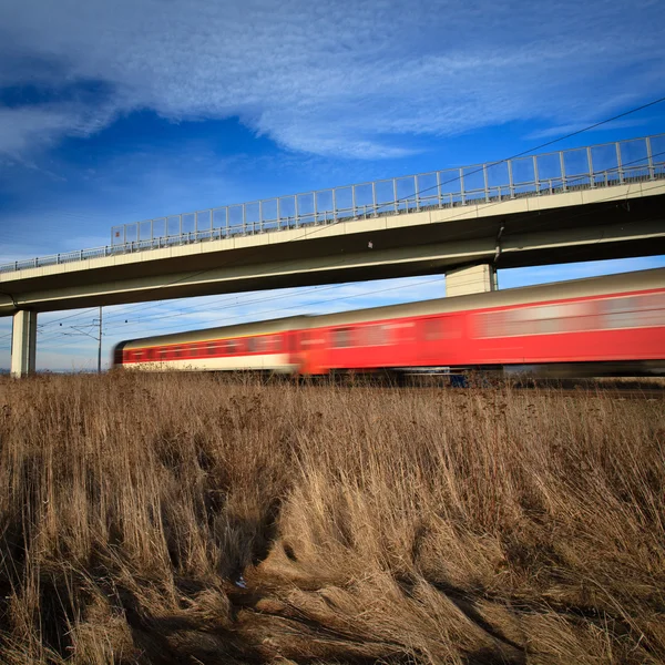 Snabba tåg passerar under en bro på en härlig sommardag — Stockfoto