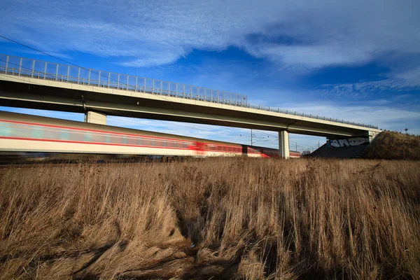 Comboio rápido passando sob uma ponte em um lindo dia de verão — Fotografia de Stock
