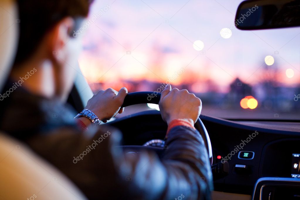 Man driving his modern car at night in a city