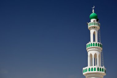 White mosque with minaret against blue sky (Sur, Oman) clipart