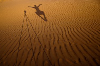 Shadow of a photographer levitating next to his tripod cast clipart