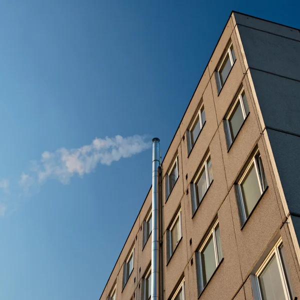 Smoke/flue gases going out of a chimney by an apartment building — Stock Photo, Image